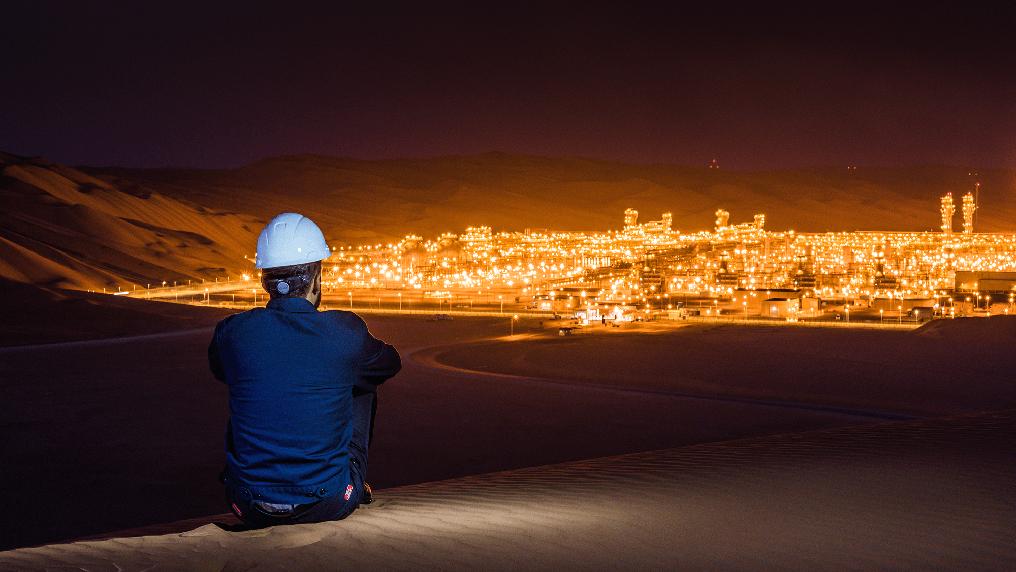 Aramco engineer overlooking Shaybah oil production site at night